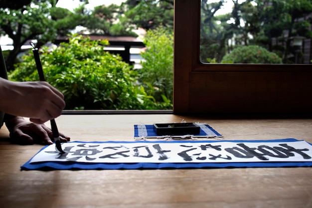 Man practicing japanese handwriting with an assortment of tools