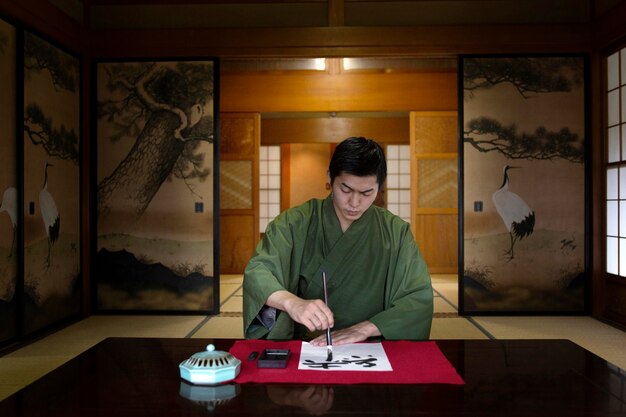 Man practicing japanese handwriting with a brush and ink