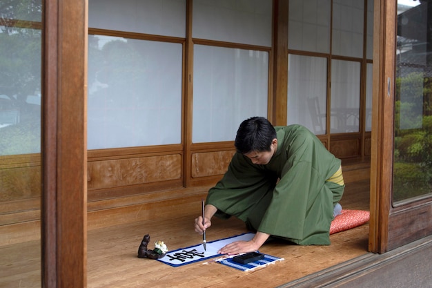 Man practicing japanese handwriting with a brush and ink