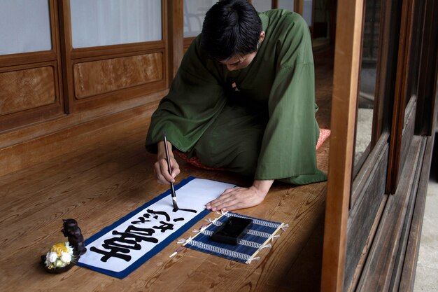 Man practicing japanese handwriting with a brush and ink