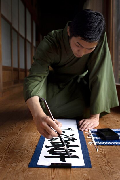 Man practicing japanese handwriting with a brush and ink