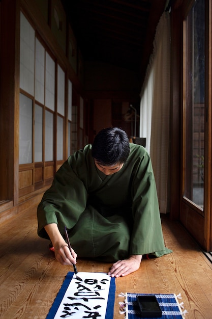 Man practicing japanese handwriting with a brush and ink