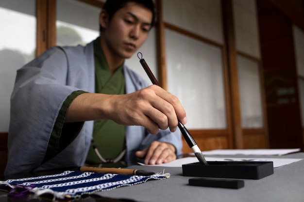 Man practicing japanese handwriting with a brush