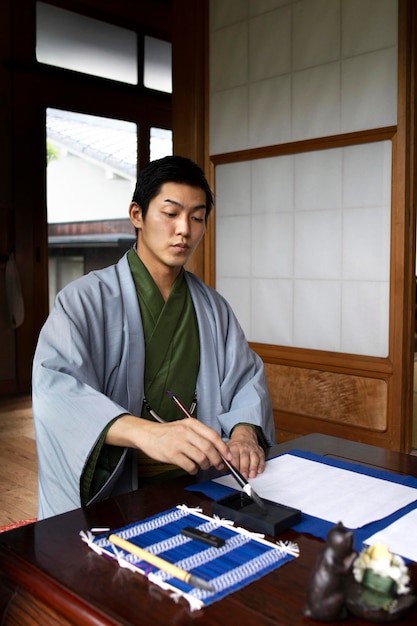 Man practicing japanese handwriting with a brush