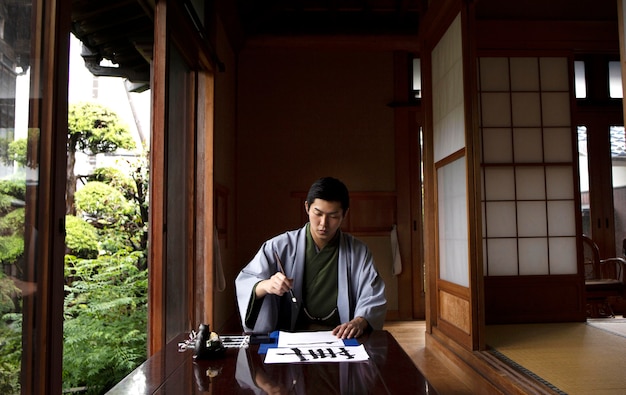 Man practicing japanese handwriting with a brush