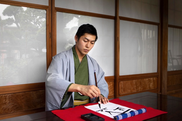 Free photo man practicing japanese handwriting with a brush