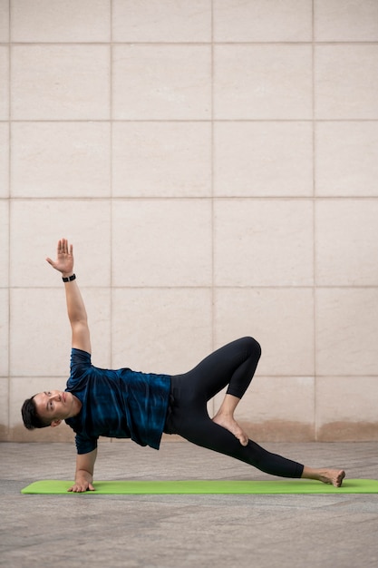 Человек, практикующий йогу на коврике на открытом воздухе с копией пространства