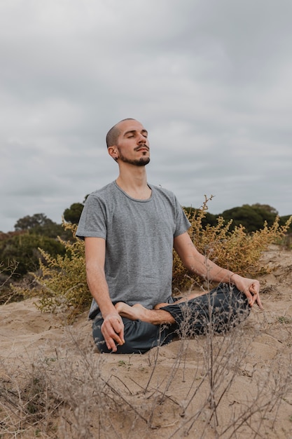 Foto gratuita l'uomo a praticare yoga all'aperto