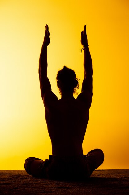 The man practicing yoga in the sunset light