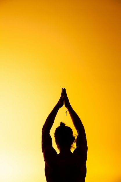 The man practicing yoga in the sunset light