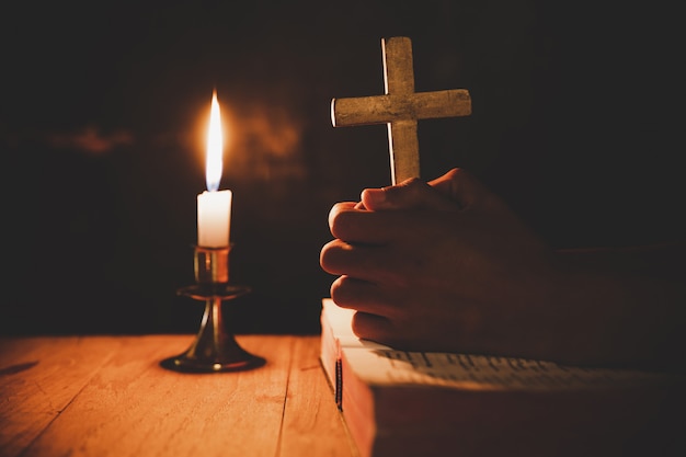 человек молится на Библии в свете свечи выборочный фокус