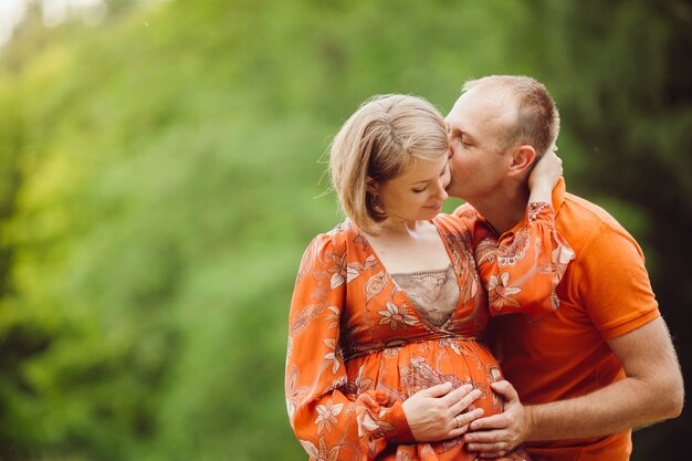 Man and pregnant woman hug each other tender in the forest 