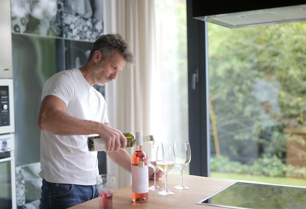 man prepares glasses of wine in the kitchen