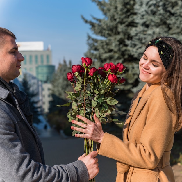 Бесплатное фото Мужчина дарит букет цветов улыбающейся женщине