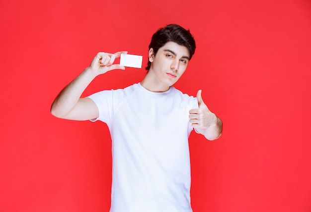 Man presenting his business card and showing successful hand signs. 