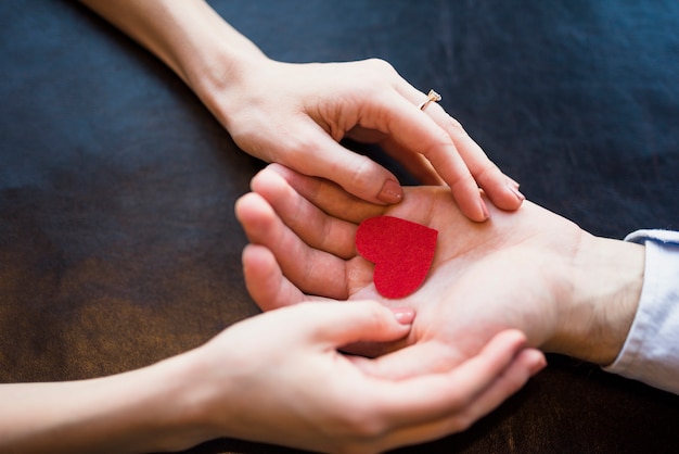 Man presenting red ornament heart to woman