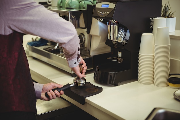 Uomo che preme il caffè con tamper nel portafiltro