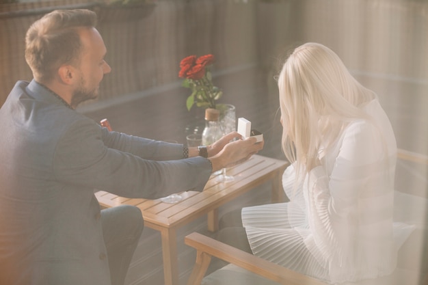 Free photo man proposing to girlfriend offering engagement ring in restaurant