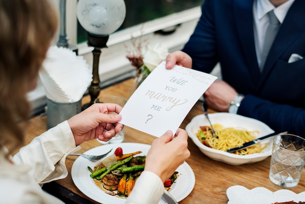 Free photo man proposing girlfriend with card