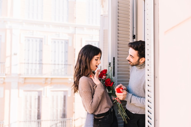 Free photo man proposing to woman on balcony