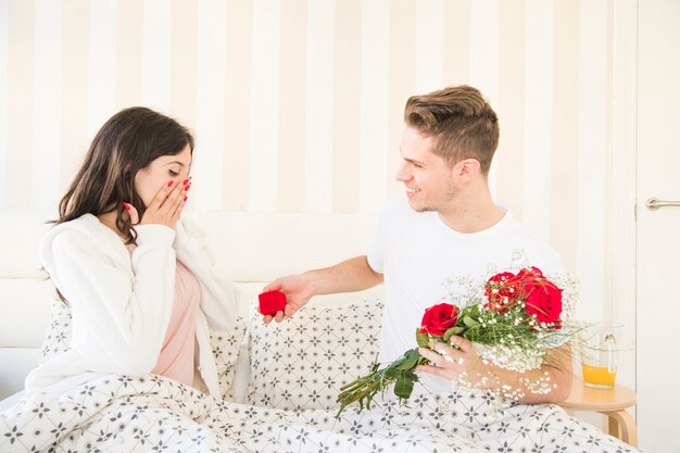 Man proposing to woman on bed