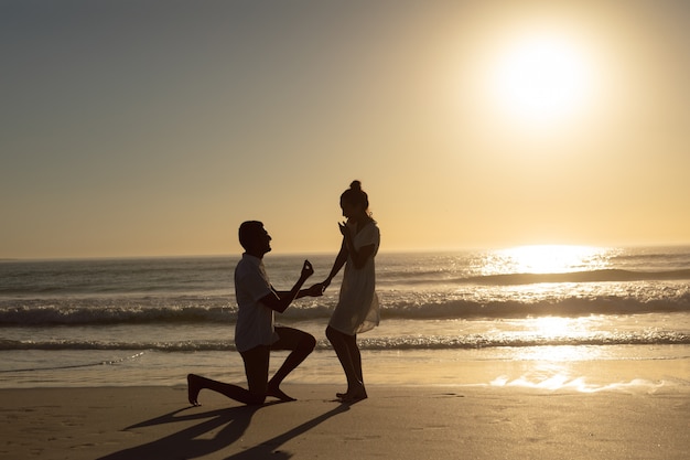 Man proposing woman at seashore on the beach