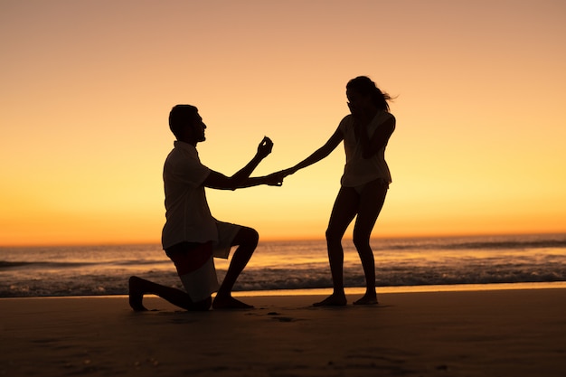 Man proposing woman at seashore on the beach