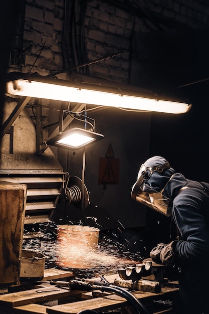 Man in protective mask is cutting metal and sparks are flying away.