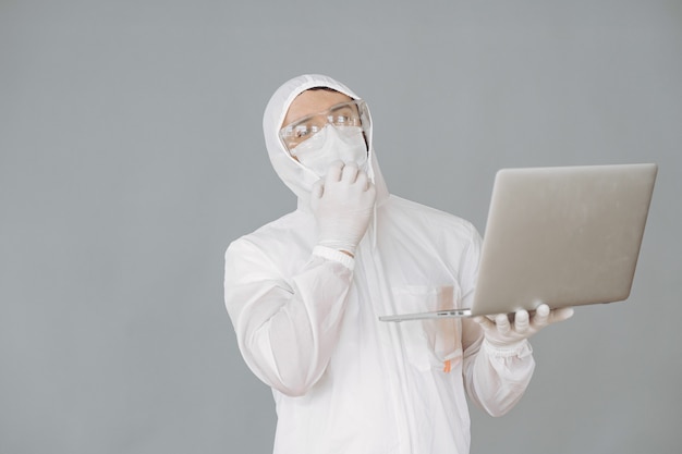 Man in protective suit and glasses on grey wall