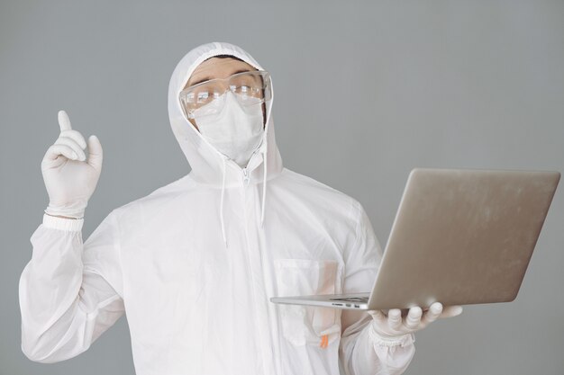 Man in protective suit and glasses on grey wall