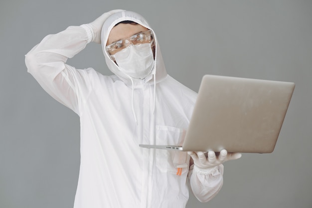 Man in protective suit and glasses on grey wall