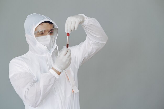 Man in protective suit and glasses on grey wall