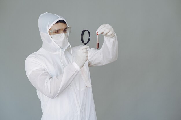 Man in protective suit and glasses on grey wall
