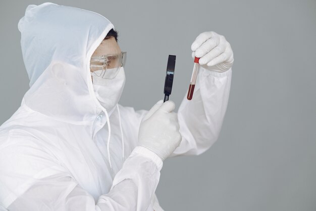 Man in protective suit and glasses on grey wall