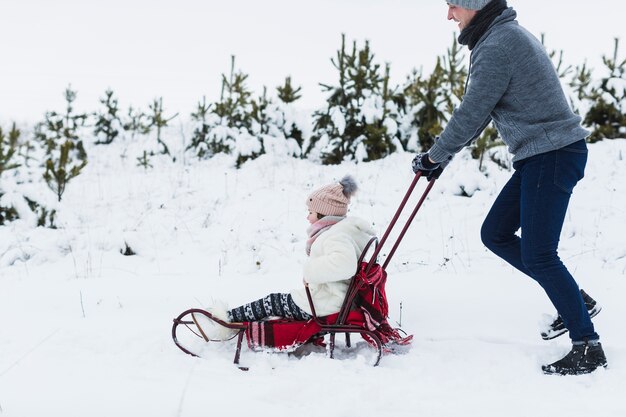 Man pulling sleigh with daughter