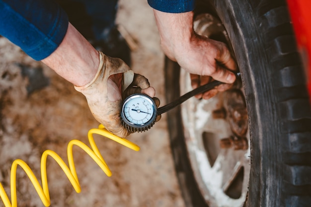 Free photo man pumps air wheel with a compressor