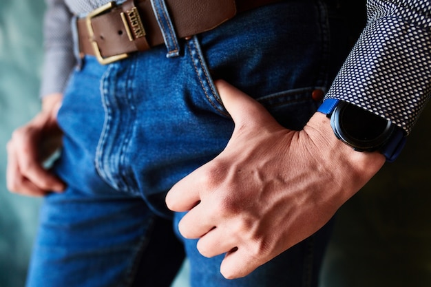 Man puts his thumbs into the pockets of jeans