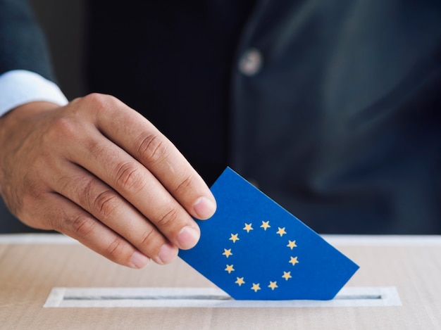 Бесплатное фото Человек кладет европейский избирательный бюллетень в коробку