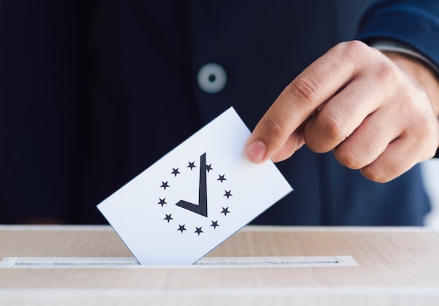 Man putting a ballot in a box close-up
