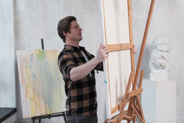 Man putting a canvas on a easel