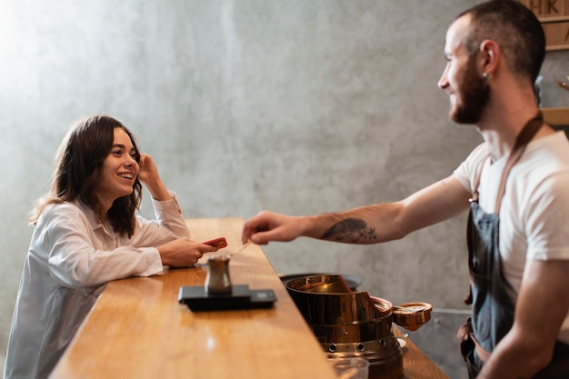 man putting coffee pot on bar with customer