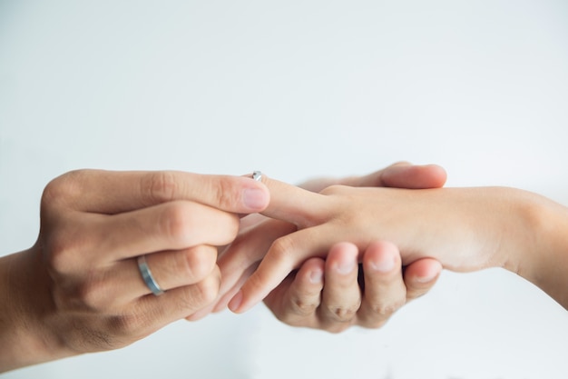 Man putting engagement ring on hand of woman