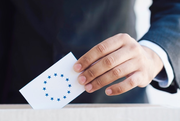 Мужчина ставит европейские избирательные бюллетени в коробку крупным планом