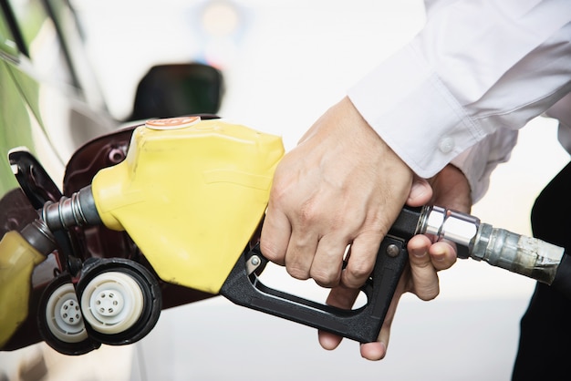 Equipaggi mettere il combustibile della benzina nella sua automobile in una stazione di servizio della pompa