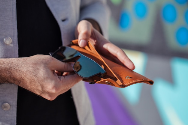 Man putting his fashion sunglasses into case