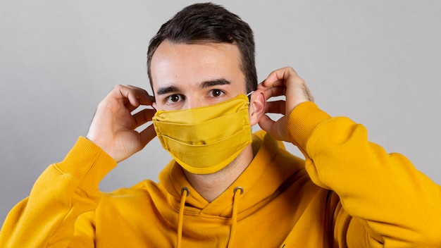 Free photo man putting on medical mask on face