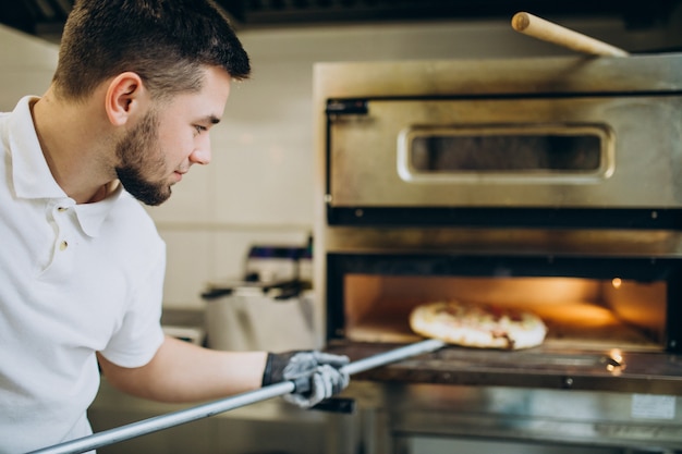 Man putting pizza in oven at pizzeria