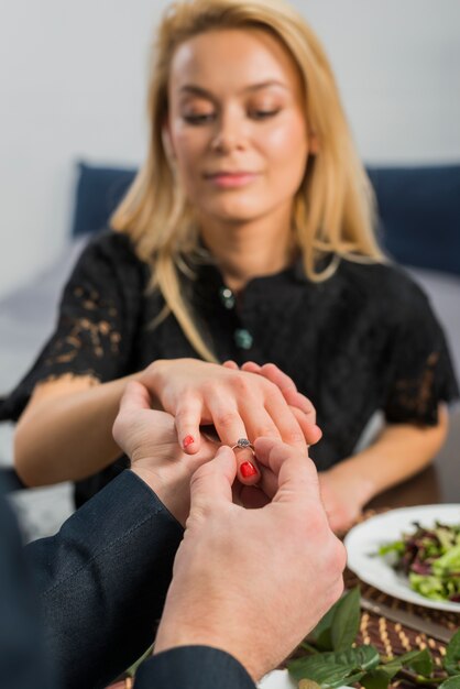テーブルで女性の指にリングを置く男