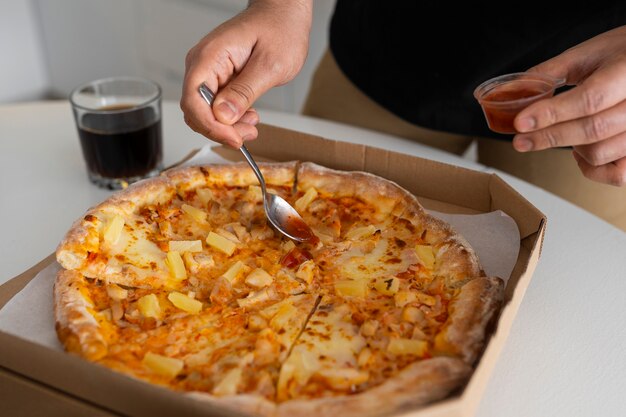 Man putting sauce on pizza