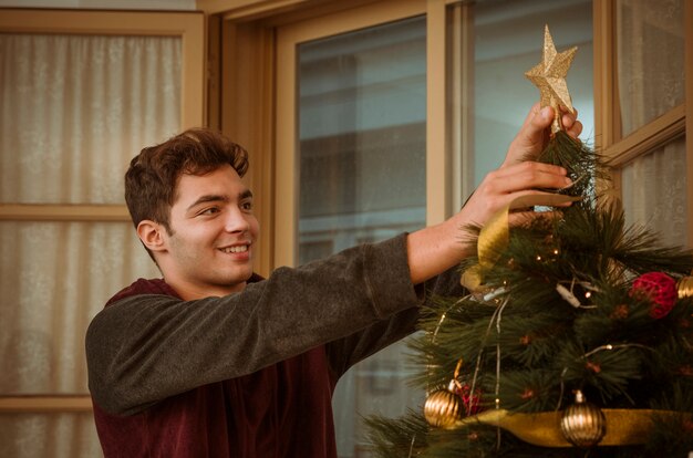 Man putting star on Christmas tree top
